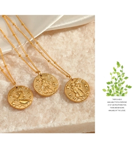 Détail macro de trois pendentifs constellation dorés sur marbre élégant et soie blanche