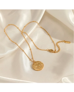 Gros plan du collier zodiaque doré en acier inoxydable avec pendentif gaufré sur soie