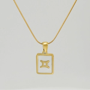 Close-up of 18K gold Gemini pendant with white shell inlay on a sleek snake chain