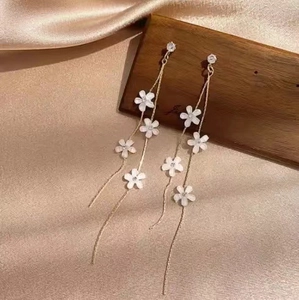 Élégantes boucles d'oreilles pompons dorées avec fleurs blanches et cristaux sur soie
