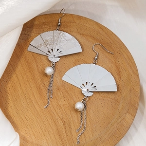 Close-up of silver fan earrings with dragon engraving, pearls and delicate tassels