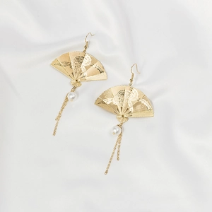 Close-up of gold fan-shaped earrings with pearl and long chain tassel on white silk