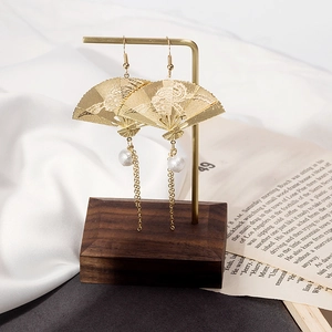 Detail of golden fan-shaped earrings with fine cloud patterns and long pearl tassels