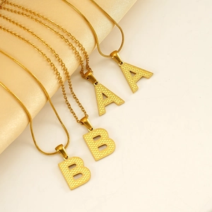 Fashionable golden letter A and B pendant necklace with snake chain on satin display