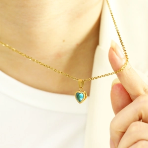 Close-up of heart-shaped sea blue zircon pendant with gold chain on model neck