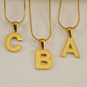 Macro detail of golden letter pendants with unique textured dots on metal surface