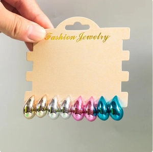 Close-up of teardrop stud earring set in gold, silver, pink, and blue metallic finishes