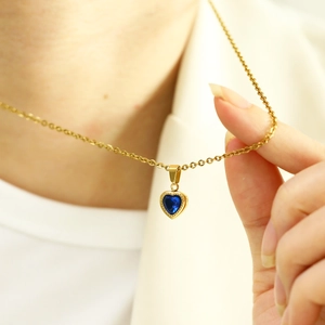 Detailed view of heart-shaped blue zircon necklace pendant with gold beaded edges
