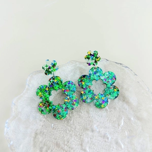 Detailweergave van acryl bloemoorbellen met groene basis en kleurrijke sterglitters