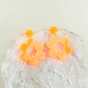 Detail van oranje acryl bloemoorbellen met holle bloemblaadjes op getextureerd glas