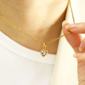 Close-up of a gold heart pendant necklace with a sparkling heart-shaped zircon stone