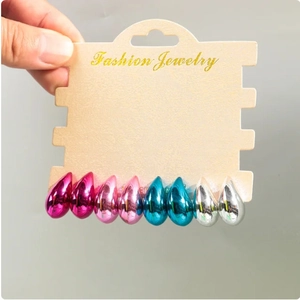 Detail of four pairs of teardrop earrings in vibrant metallic finishes on display card
