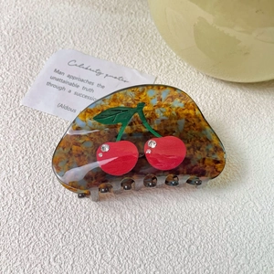 Detail of acetate hair claw clip with cherry motif and sparkling rhinestones
