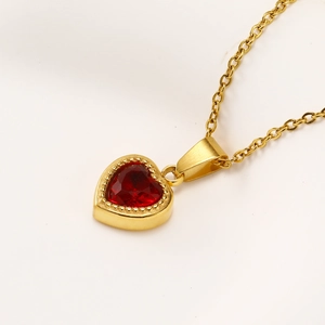 Detail of gold O-chain necklace with heart-shaped pendant and red zircon stone