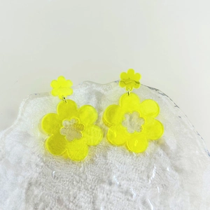 Detailopname van gele acryl bloemenoorbellen op een plateau met een ijsachtige textuur