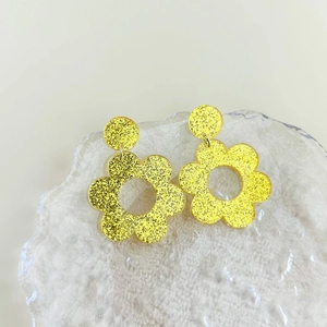 Macro-opname van gele acryl bloemoorbellen met glinsterende glitter op kristallen tray