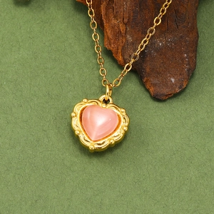 Détail macro d'un pendentif cœur en opale rose vintage dans un cadre doré 18 carats