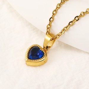 Macro shot of gold necklace with a deep blue heart gemstone and beaded vintage pendant