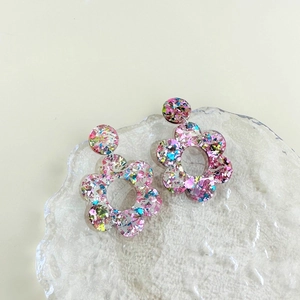 Macro-opname van acryl bloemenoorbellen met kleurrijke glitters en opengewerkt design