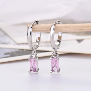 Detail of elegant silver drop earrings with rectangular pink zircon crystals on a wooden stand