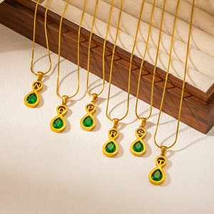 Gold alphabet necklace featuring infinity pendant and emerald drop on a snake chain