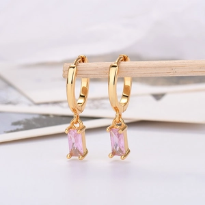 Detail of gold hoop earrings featuring rectangular pink zircon pendant on a wooden stand