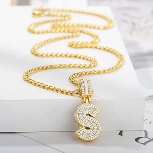 Macro detail of golden letter S pendant with zircon stones on a twisted rope chain