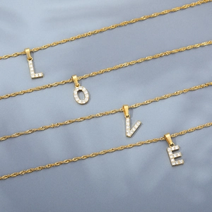 Dettaglio di quattro catene dorate a onde con ciondoli a lettere LOVE con cristalli