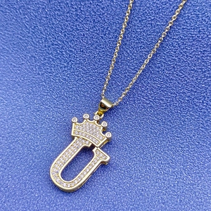 Gros plan du pendentif couronne lettre U plaqué or 18 carats avec cristaux brillants