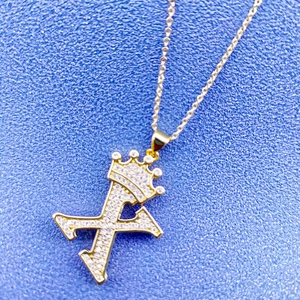 Vue macro du pendentif couronne lettre X doré à l'or fin avec cristaux de zircon