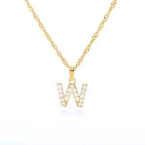 Dettaglio di una collana a catena dorata con ciondolo a forma di lettera W e zirconi lucidi