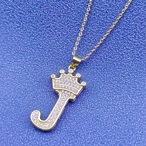 Macro d'un pendentif couronne lettre J plaqué or 18k avec des zircons étincelants