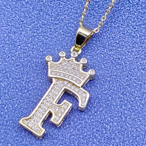 Vue détaillée du pendentif lettre F dorée avec couronne et zircons scintillants