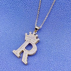 Détail du pendentif couronne lettre R en or 18k avec incrustation de cristaux brillants