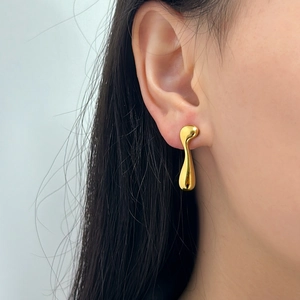 Gros plan de boucles d'oreilles dorées irrégulières avec une texture métallique fondue