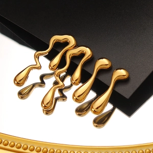 Détail macro de boucles d'oreilles vagues fluides irrégulières en or poli sur miroir