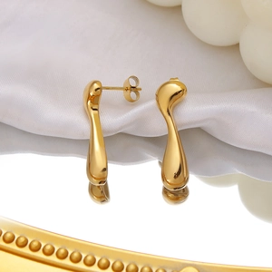 Détails macro de boucles d'oreilles dorées irrégulières sur soie blanche et reflets