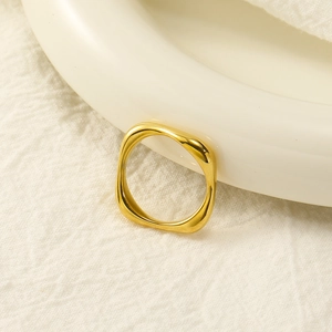 Detailed view of polished 18k gold geometric square ring on a white ceramic base
