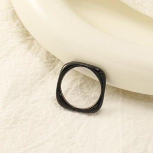 Minimalist black square-round titanium ring with a glossy finish on white fabric