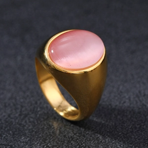 Detail view of pink cat eye stone set in a wide golden vintage stainless steel ring