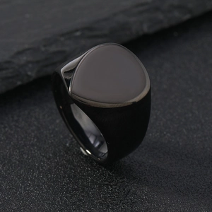 Macro detail of men's matte black stainless steel signet ring on a dark stone surface