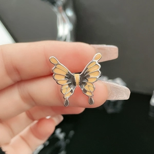 Macro detail of silver ring with yellow enamel butterfly and intricate black patterns