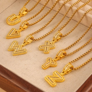 Collana a catena box dorata con ciondoli a lettera in zirconi da U a Z su vassoio beige