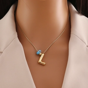 Gros plan du collier en or 18 carats avec pendentif lettre L et perle œil bleu sur mannequin
