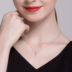 Close-up of a silver cross necklace with pavé zircon stones on a refined cable chain