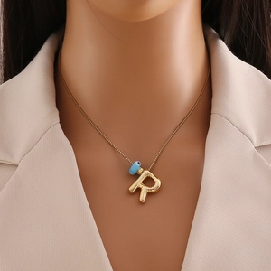 Détail du collier avec pendentif lettre R style ballon doré 18k et petite perle bleue