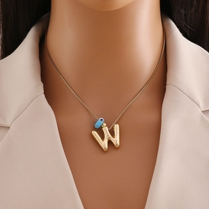 Détail du collier en or 18k avec pendentif lettre W et perle d'œil bleu sur la chaîne