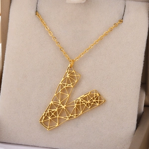 Detail van gouden geometrische holle letter V-hanger aan ketting op fluweel