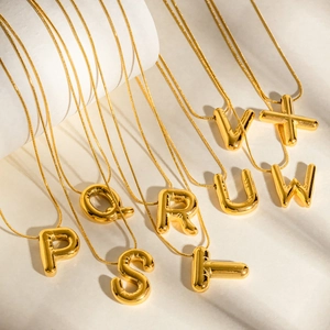 Close-up of golden balloon style letter pendants on elegant polished snake chains