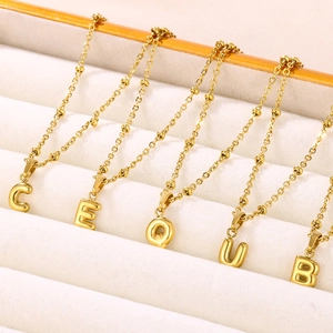 Detailed view of 18K gold plated bubble letter pendants on delicate beaded chains